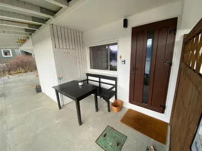 a porch with a table and a bench next to a door at Great place with a stunning view of the mountains and the fjord in Ålesund