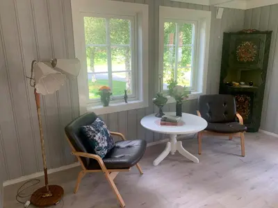 a room with two chairs and a table and two windows at Engen Gård in Innfjorden