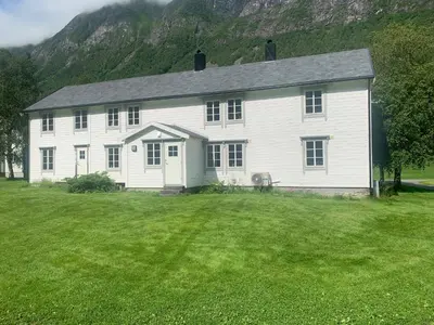 a large white house with a grass yard at Engen Gård in Innfjorden