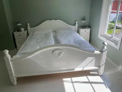 a white bed in a bedroom with two night stands at Engen Gård in Innfjorden
