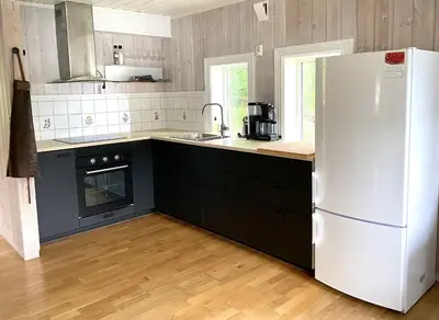 a kitchen with a white refrigerator and black cabinets at Stryn - Faleide -hytte med fjord og fjell utsikt in Stryn
