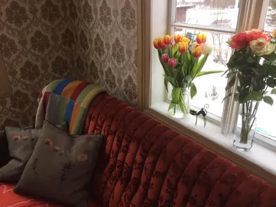 a couch sitting in front of a window with flowers at Overvoll Farm in Stranda