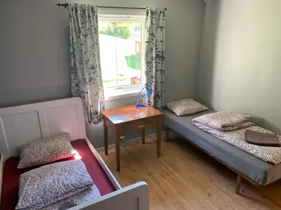 a room with two beds and a table and a window at Feriehus med utsikt til fjord og fjell in Gvammen