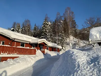 a house covered in snow with a pile of snow at Feriehus med utsikt til fjord og fjell in Gvammen