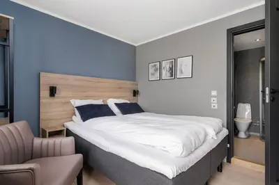 a bedroom with a large bed and a chair at Frich's Rudshøgda in Ringsaker