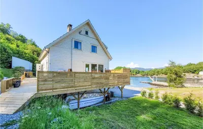 a house on a dock with a boat on the water at Nice Home In Fitjar With House Sea View in Fitjar
