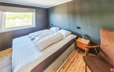 a bedroom with a bed and a window and a chair at Nice Home In Fitjar With House Sea View in Fitjar