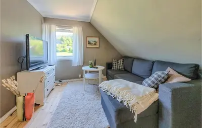 a living room with a blue couch and a tv at Nice Home In Fitjar With House Sea View in Fitjar