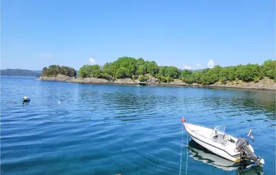 a white boat sitting in the middle of a lake at Nice Home In Fitjar With House Sea View in Fitjar