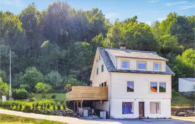 a white house with a gambrel roof at Nice Home In Fitjar With House Sea View in Fitjar