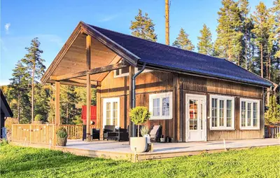 a small wooden house with a large deck at Cozy Home In Brøttum With Kitchen