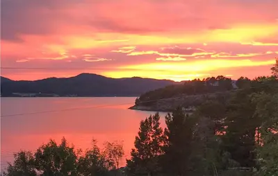 a sunset over a body of water with trees at 1 Bedroom Amazing Apartment In Øydegard in Aspa