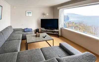 a living room with a couch and a large window at 5 Bedroom Amazing Home In Strandebarm in Strandebarm