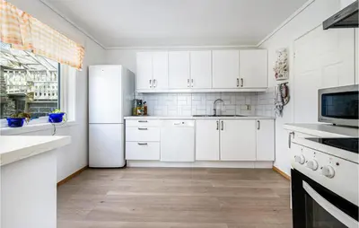 a kitchen with white cabinets and a white refrigerator at 5 Bedroom Amazing Home In Strandebarm in Strandebarm