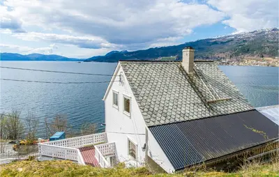 an old house with solar panels on the side of a lake at 5 Bedroom Amazing Home In Strandebarm in Strandebarm