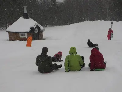 a group of people sitting in the snow in front of a cabin at Skåbu Camping in Skåbu