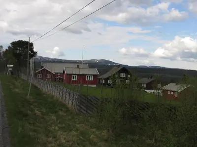 a group of houses on a hill with a fence at Skåbu Camping in Skåbu