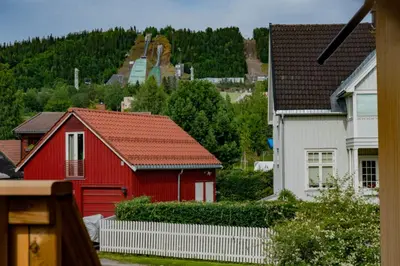 a red house and two white houses and trees at Sanns villa in Lillehammer