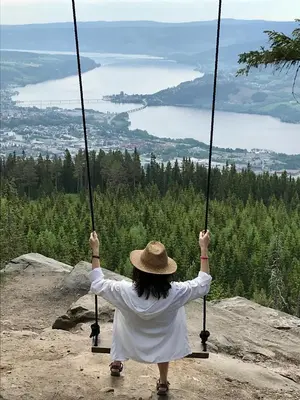 a woman in a hat sitting on a swing at Sanns villa in Lillehammer
