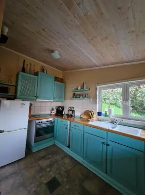 a kitchen with blue cabinets and a white refrigerator at Stranda apartment in Stranda