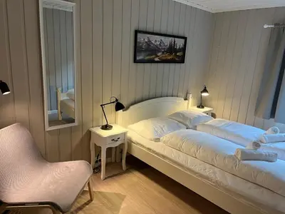 a bedroom with two beds and a chair and a mirror at Nørdre-Repp in Boverdalen
