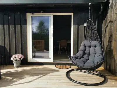 a swing hanging on a porch with a patio at Flott hytte sentralt i Hallingdal in Ål