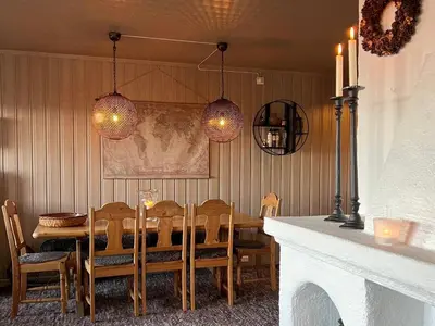 a dining room with a table and chairs and lights at Bjødnabakkens fjellutsikt in Beitostøl