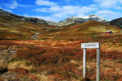 a sign in the middle of a field with a mountain at Beitotind sentralt på Beitostølen in Beitostøl