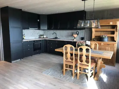 a kitchen with black cabinets and a wooden table and chairs at Beitotind sentralt på Beitostølen in Beitostøl