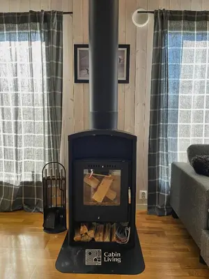a wood stove in a living room with a couch at Family friendly cabin Hemsedal GolfAlpin golf, ski-out, fireplace & wifi in Hemsedal