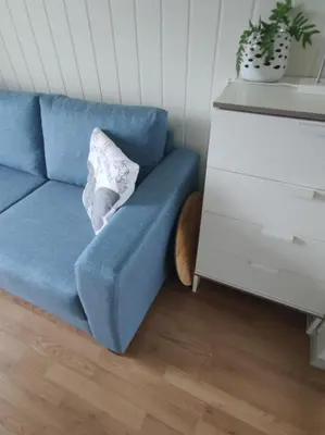 a blue couch with a pillow sitting next to a dresser at Guest room in private house in Ålesund
