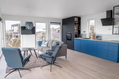 a kitchen with blue cabinets and a couch and a table at Runde Panorama - Trollvogga in Runde