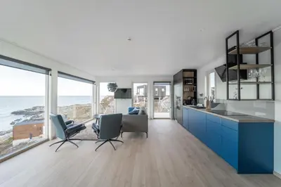 a kitchen with blue cabinets and a view of the ocean at Runde Panorama - Trollvogga in Runde
