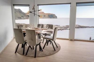 a dining room with a table and chairs and the ocean at Runde Panorama - Trollvogga in Runde