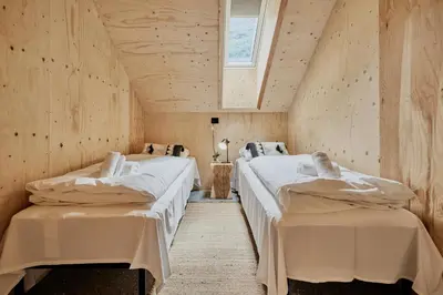 two beds in a room with wooden walls at Lodgen Stryn in Stryn