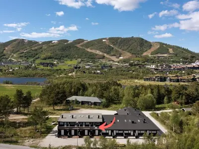 an aerial view of a building with mountains in the background at Flott leilighet i Vestlia - ski in/ski out in Geilo