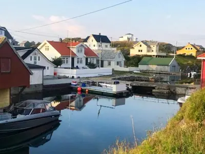 a boat is docked in a marina with houses at 6 person holiday home in Hernar-By Traum in Bøvågen