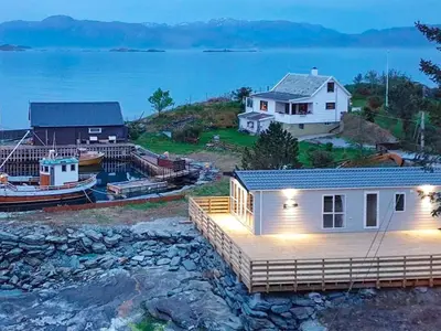 a house with a dock and a boat in the water at 6 person holiday home in Tansøy-By Traum in Tansøy