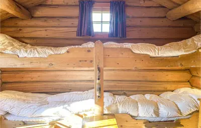 a large bed in a log cabin with a window at 3 Bedroom Nice Home In Kvam in Kvam