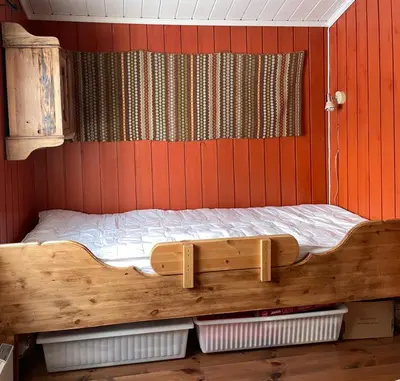 a wooden bed in a room with red walls at Vasethytta - cabin with a lovely view in Ron