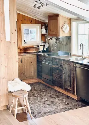 a kitchen with wooden cabinets and a stool and a sink at Vasethytta - cabin with a lovely view in Ron