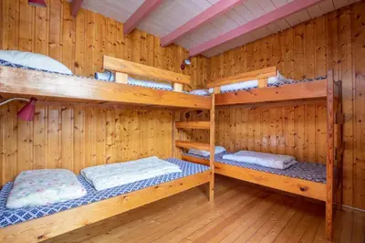 a wooden room with three bunk beds in it at Pluscamp Sandvik in Gaupne