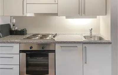 a kitchen with white cabinets and a stove and a sink at Stunning Apartment In Lillehammer in Lillehammer