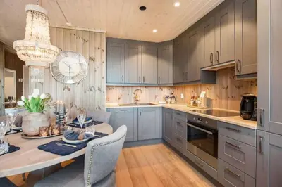 a kitchen with blue cabinets and a table and chairs at Flott fritidsleilighet i Bualie på Golsfjellet in Gol