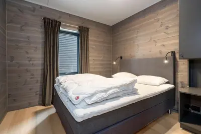 a bedroom with a large bed with white sheets at Riddertunet apartment 101 in Beitostøl