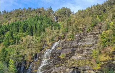 a waterfall on the side of a mountain at 4 Bedroom Lovely Home In Strandebarm in Strandebarm