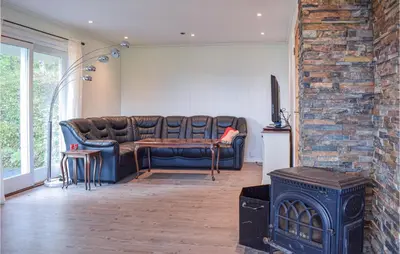 a living room with a couch and a fireplace at 4 Bedroom Lovely Home In Strandebarm in Strandebarm