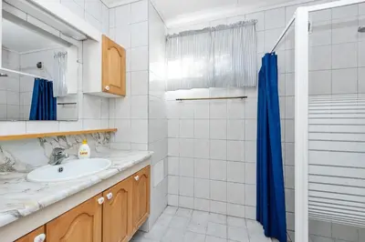 a bathroom with a sink and a blue shower curtain at Flemsøy in Ålesund
