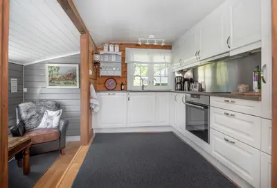 a kitchen with white cabinets and a chair at Økslevegen 2 in Stranda