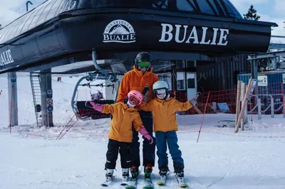a man and two children on skis in front of a ski lift at Bualie Golsfjellet in Gol